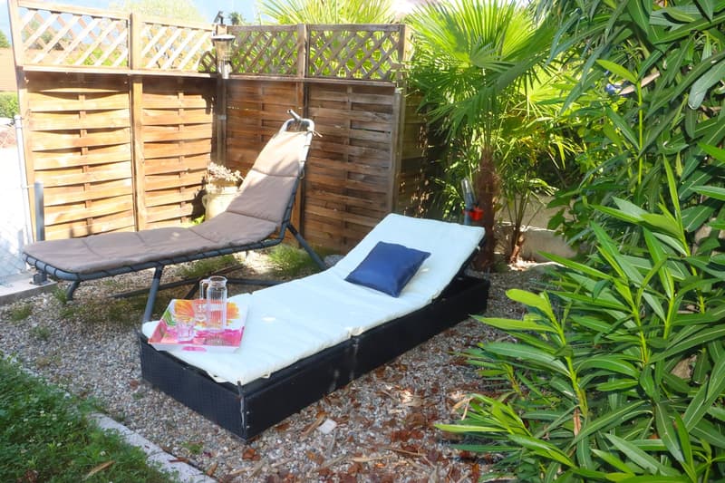 outdoor relaxation area with lounge chairs, small plants, wooden fence, pebbled flooring