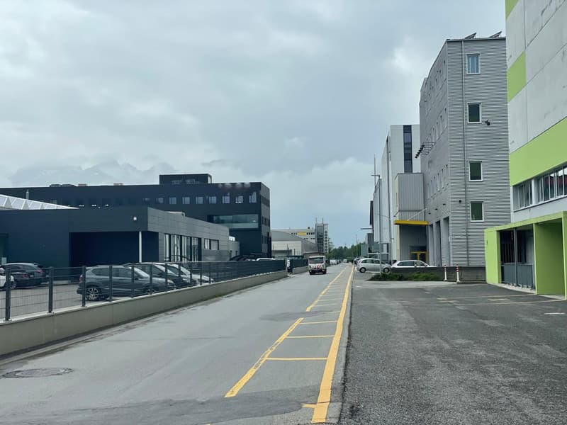 multiple buildings, parking area, cars parked, road, fences, overcast sky