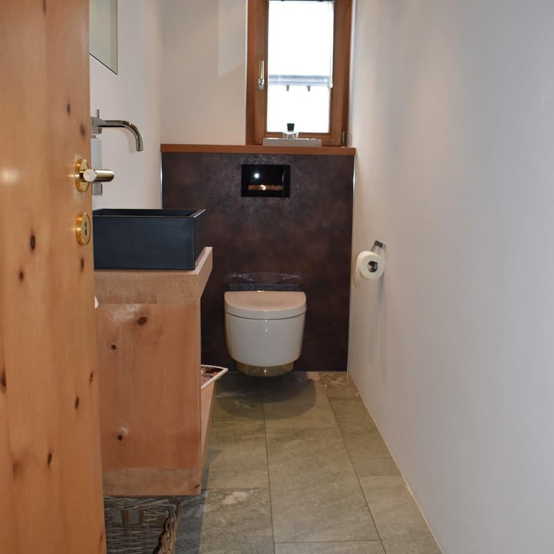 small toilet, sink, wooden cabinet, floor basket, window