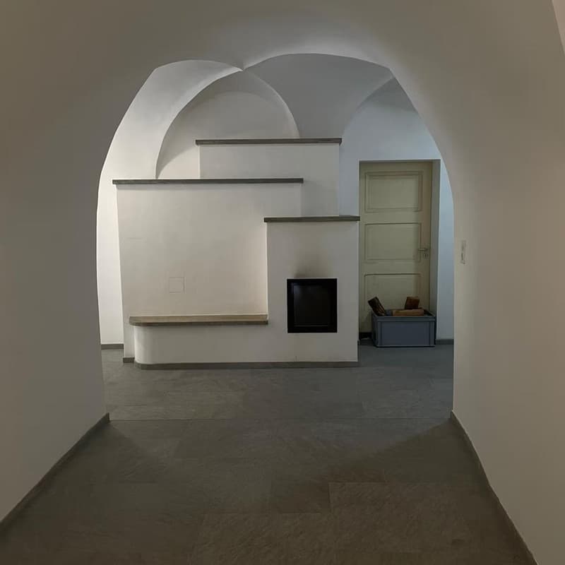 arched corridor, white walls, gray tiles, fireplace, shelf, wooden door