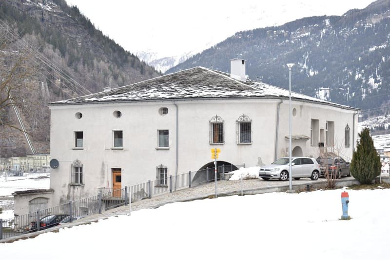 white painted facade, tiled roof, multiple windows, arch entrance, covered entrance, snow-covered ground, multiple cars parked, chimney