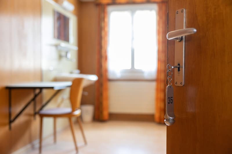 Wooden interior, desk, chair, window with view, room number 35 on door