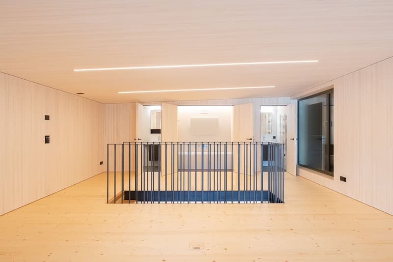 light color wall, white wooden panelling, high ceiling, open balcony, wooden floor, black railing, open bathroom area