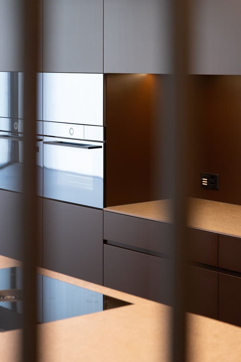 Modern kitchen with built-in appliances, dark cabinets, and a light countertop surface.