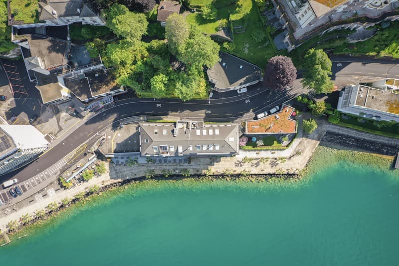 Aerial view of a building complex with multiple buildings, green spaces, and a waterfront area.