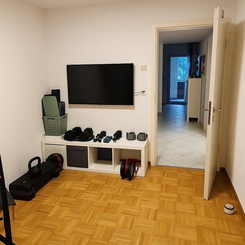 room with open door, workout equipment, wooden floor, white wall, TV on wall