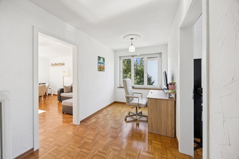 Modern office room with desk, swivel chair, lamp, wooden floor, white walls, windows with glass doors