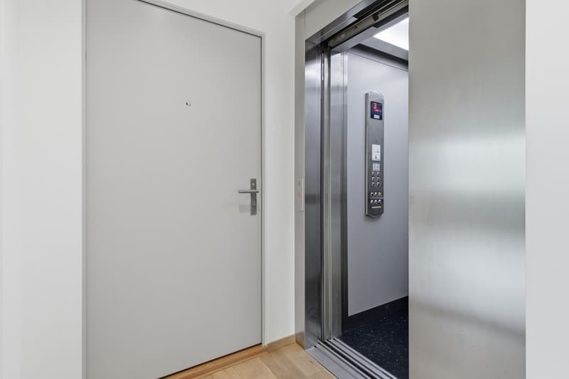 Modern elevator with a white door and a silver control panel