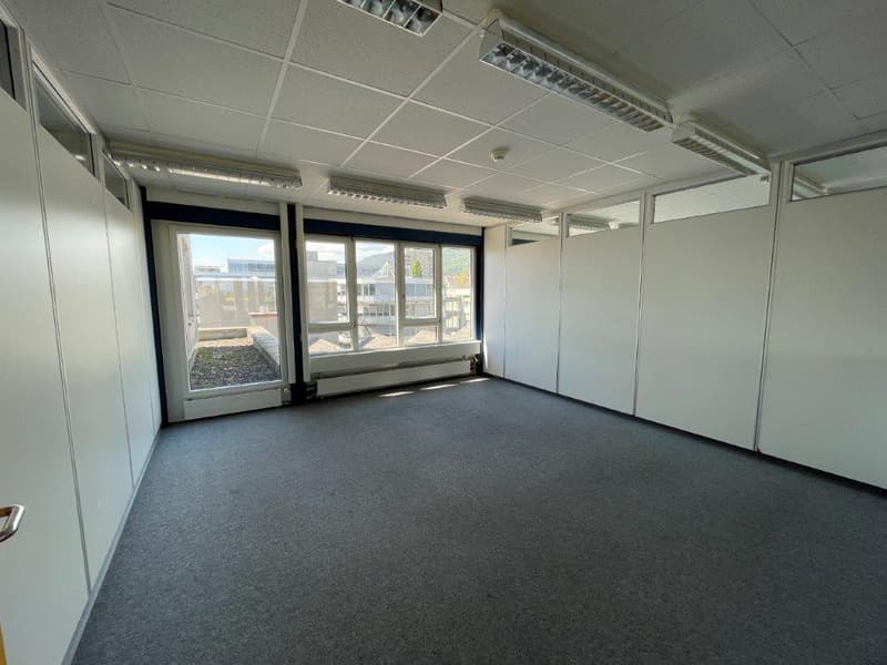 empty room, fluorescent ceiling lights, glass door, large windows, gray floor