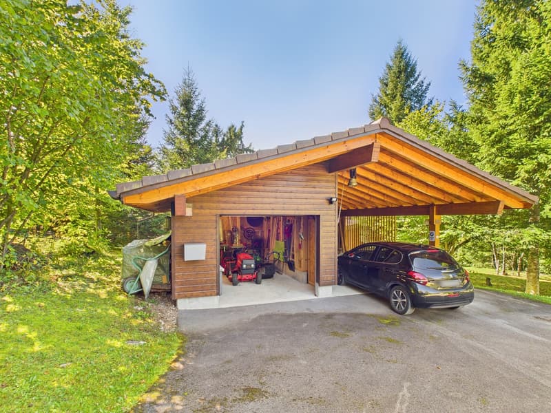 wooden garage with a covered entrance, black car parked in front, tools and machinery inside