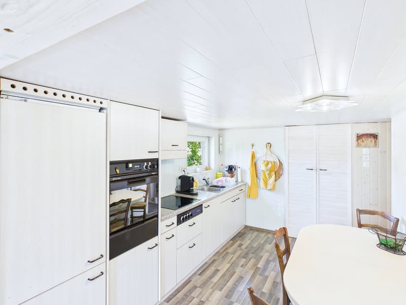 White cabinets, wooden floors, white countertops, built-in oven and dishwasher, modern sink, white refrigerator, white ceiling