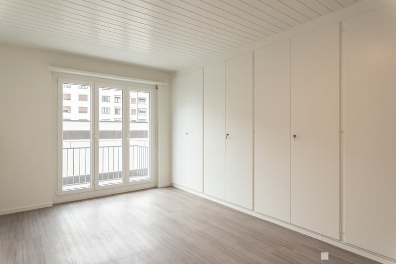 empty room, wooden floor, sliding glass doors, balcony, white walls, built-in wardrobes