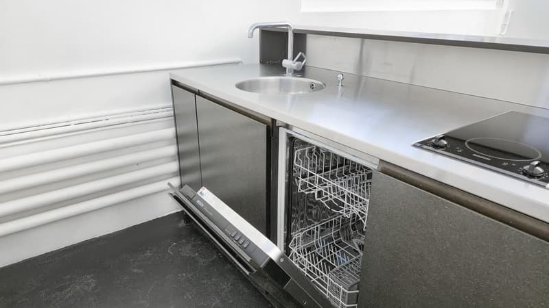 Stainless steel countertop, sink with faucet, gas stove, open dishwasher