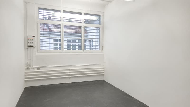 empty room with white walls, windows, grey floor and hanging lamps