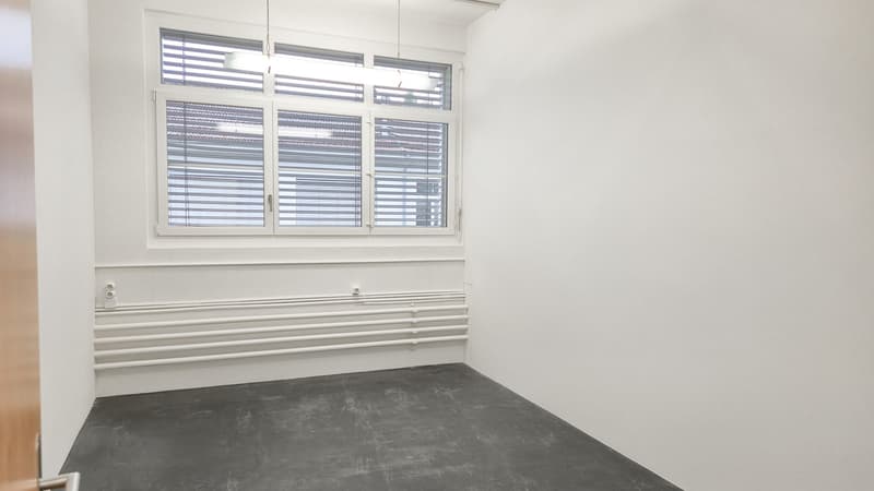 Empty room with white walls, gray floor, a window with white shutters, and white pipes