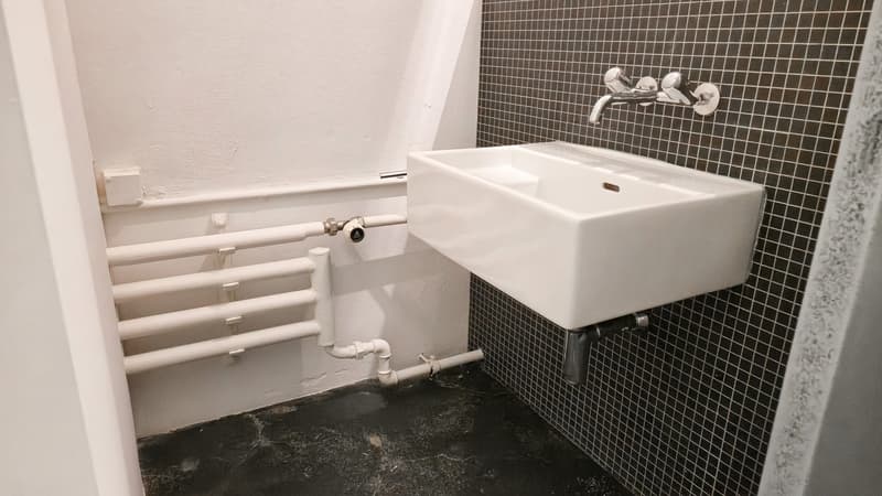 white sink with a faucet on the wall, radiator on the wall, tiled wall, white floor