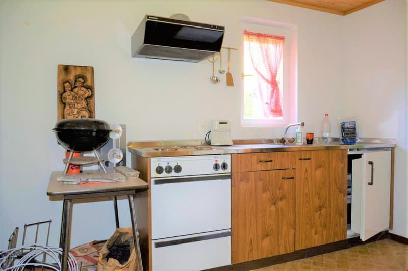 kitchen with stove, sink, cabinets, window, and a small table with a grill on it