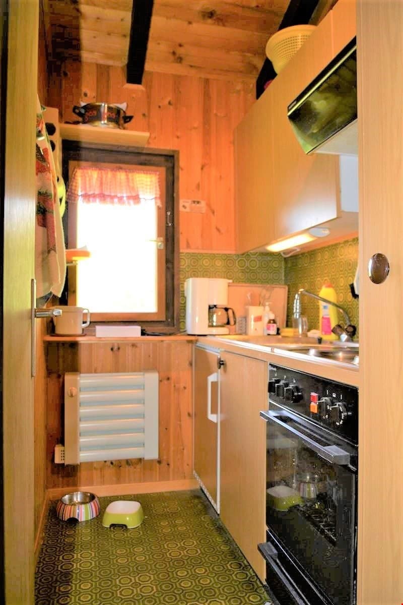 small kitchen with wooden walls, sink, oven, coffee machine, window, radiator