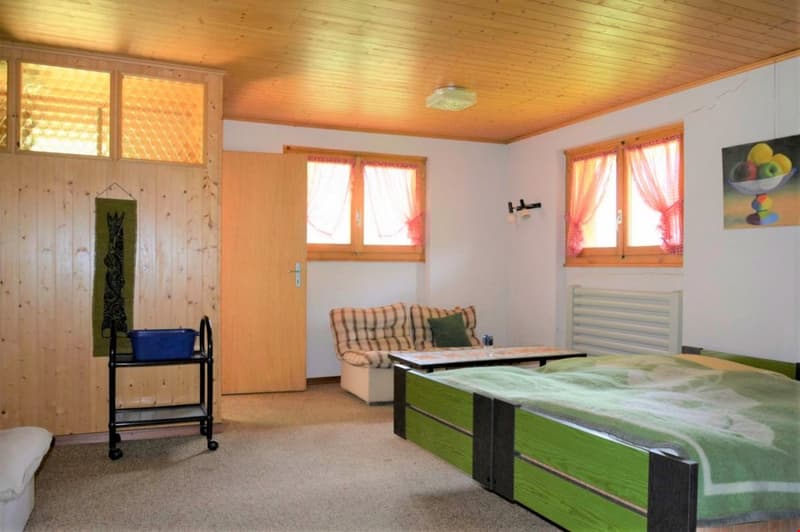 bedroom with two beds, couch, table, wooden walls, windows with curtains