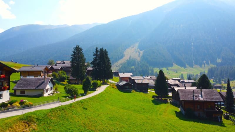 Wooden houses in mountain valley with view of mountain peaks