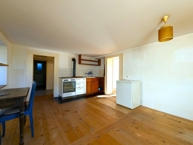 Open kitchen with wooden floors, white walls, stove, oven, refrigerator, and wooden cabinets