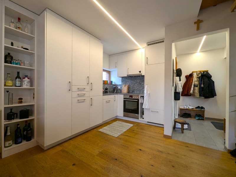 Spacious kitchen with white cabinets, granite countertops, stainless steel appliances including a dishwasher, and hardwood flooring. The room also has a cross on the wall, indicating a religious or spiritual element.