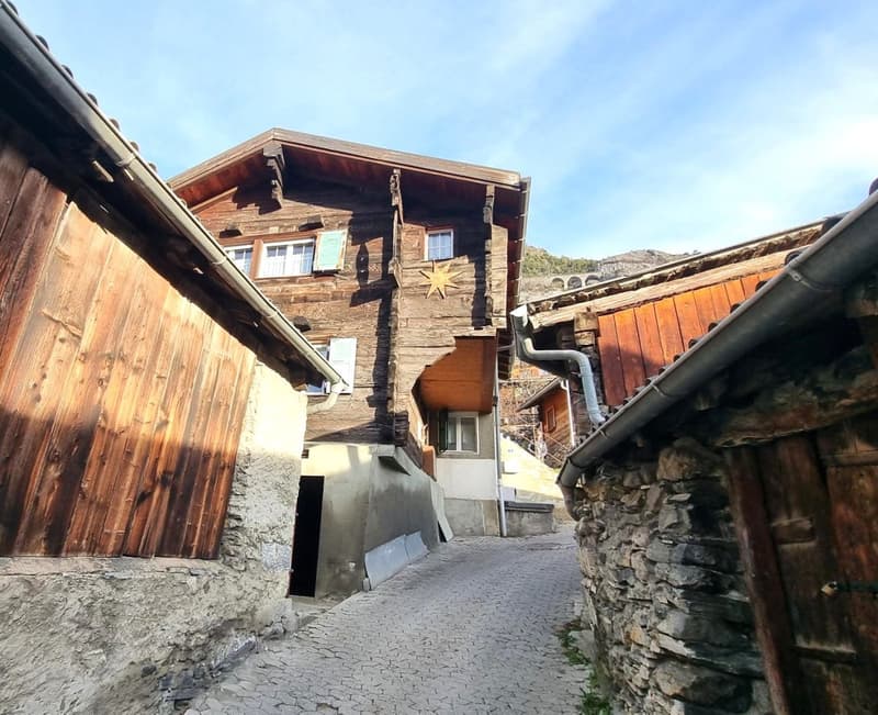 2 story wooden chalet-style house with stone and wood exterior, balcony, and decorative star on the roof