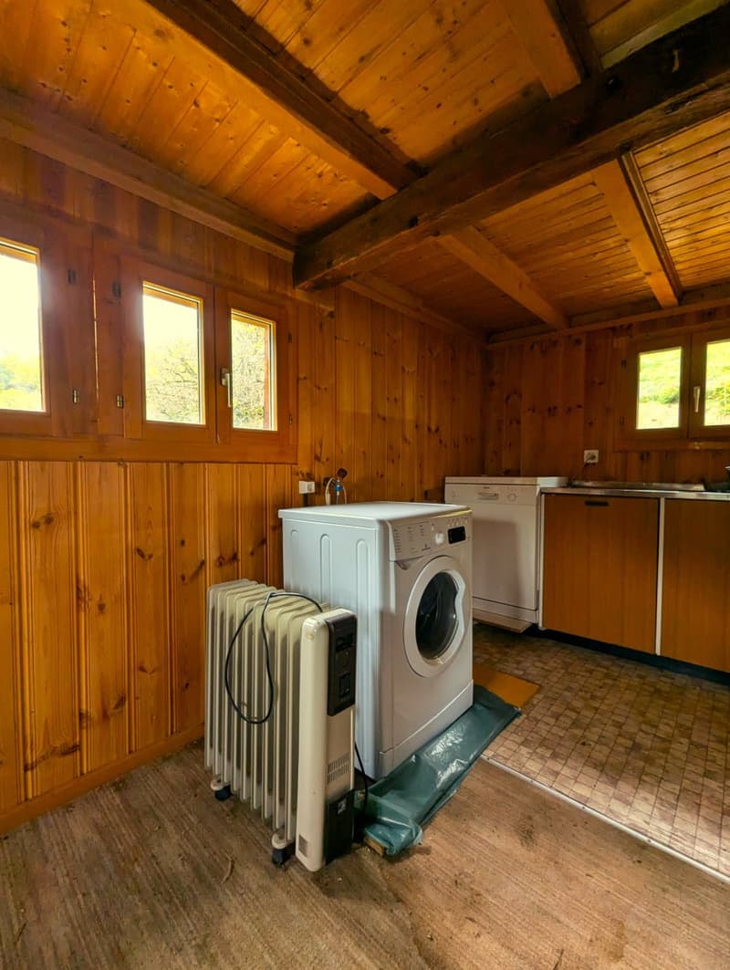 Two white washing machines and a heater are present. Walls are made of wood.