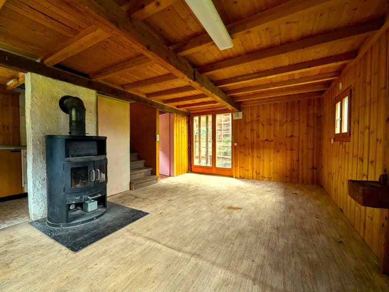 wooden walls, wooden floor, black fireplace, two glass doors, wooden stairs