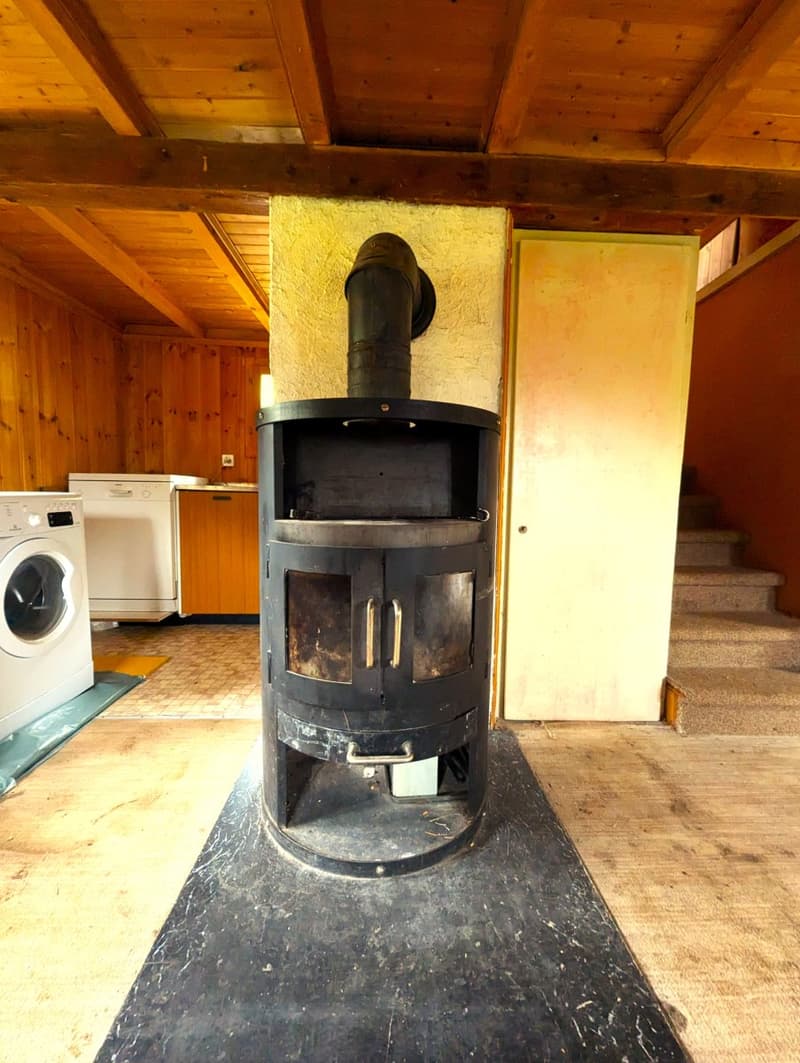 A wood burning fireplace, tile floor, stairs, white washing machine, dishwasher, and wood paneled walls.