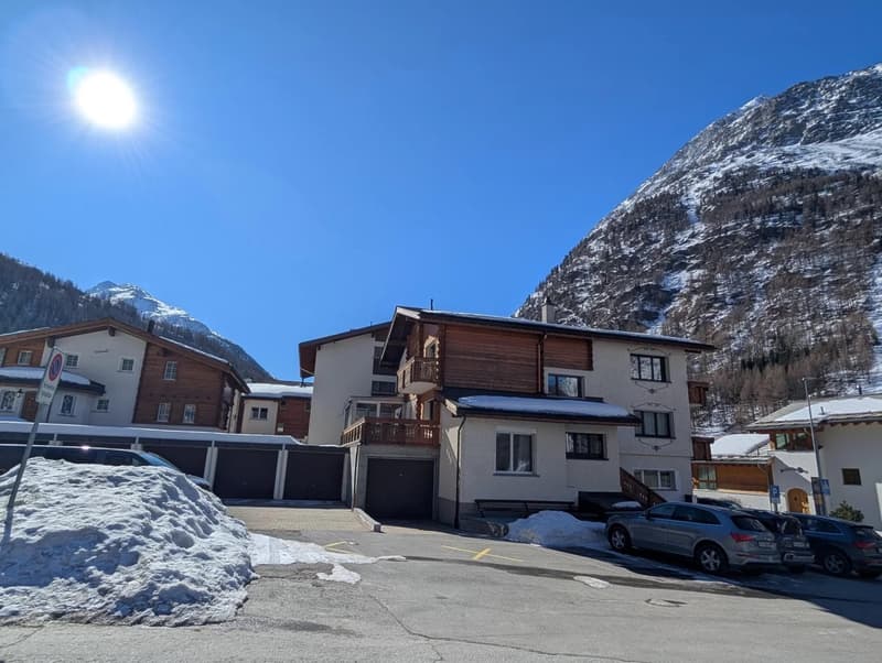 Mountain resort style house, two garages, ground floor living space, snowy mountains in background, parking lot