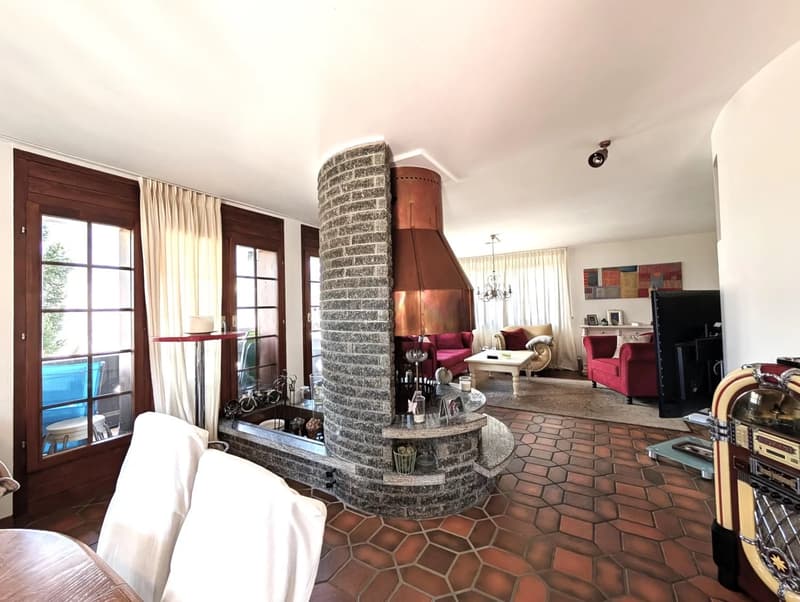 Living room, white walls, fireplace, brick column, tile flooring, sofa, coffee table, curtains, chandelier, artwork, jukebox, table, chairs