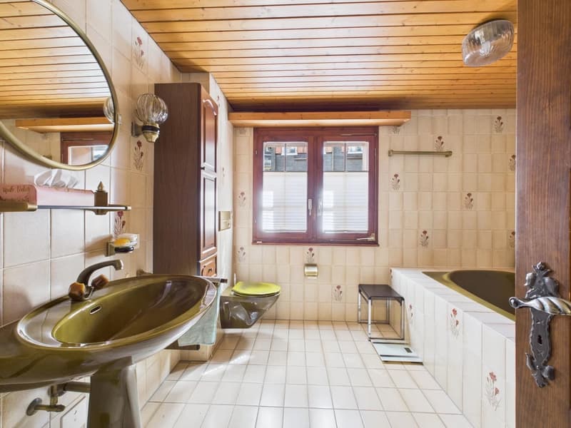 white tiled walls, wooden ceiling, round sink, green basin, white bathtub, toilet, window with wooden frame, mirror, open door