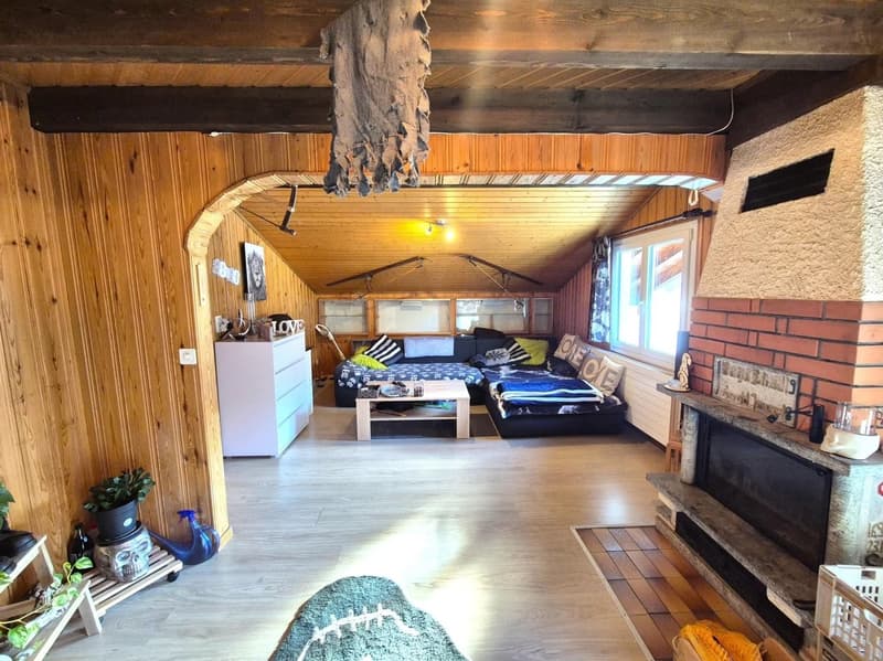 Cozy wooden cabin-style studio with a fireplace, wooden walls and ceiling, a bed, a coffee table, and various decor items.
