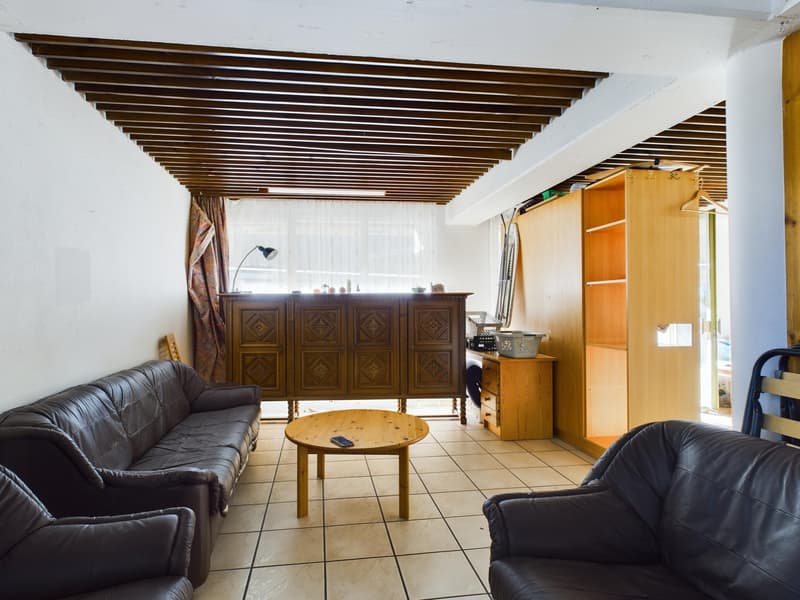 Spacious living room with wooden beamed ceiling, leather sofas, wooden cabinet, and a coffee table on tiled flooring