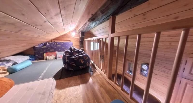 Wooden beams and paneled walls, storage space with various items, railing along the edge