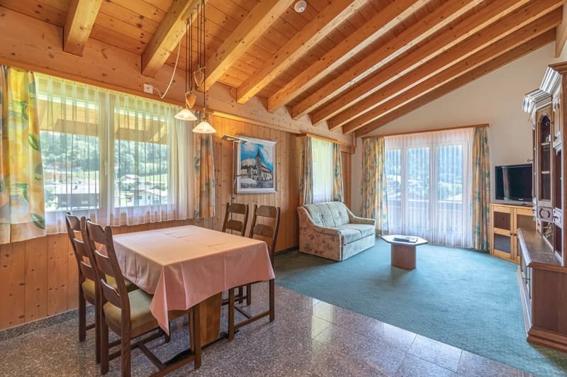Spacious living room with wooden beamed ceiling, large windows, dining table, sofa, and TV cabinet