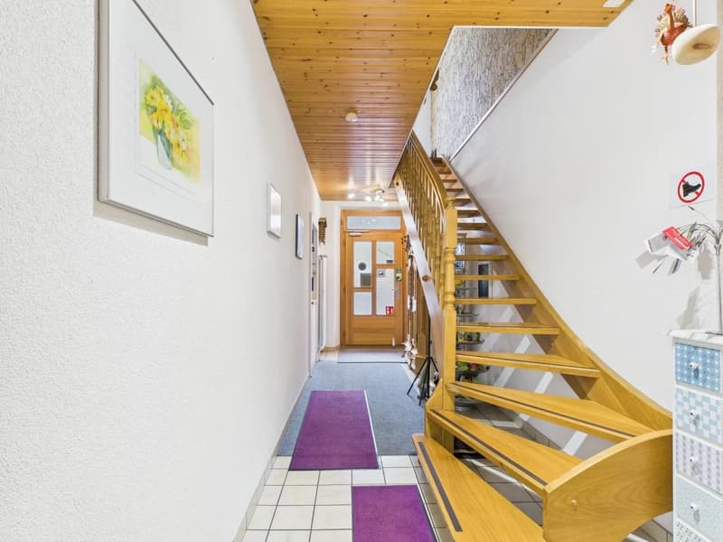 tiled hallway, wood flooring, wooden spiral staircase, doors, picture frames, purple rugs, ceiling lights