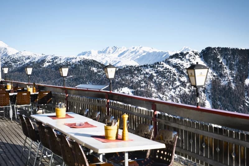 outdoor dining tables and chairs, wooden floor, fenced railings, mountain view