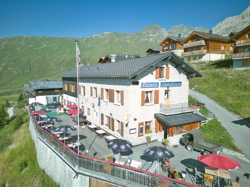 Mountainside lodge, large outdoor dining area with tables and chairs, mountains in the background