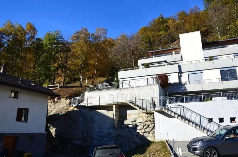 modern multistory building, stairs to entrance, concrete wall, two parked cars