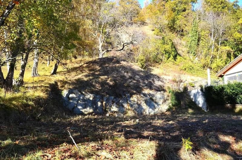 natural hilly terrain, with greenery, a small hill, and a rustic structure