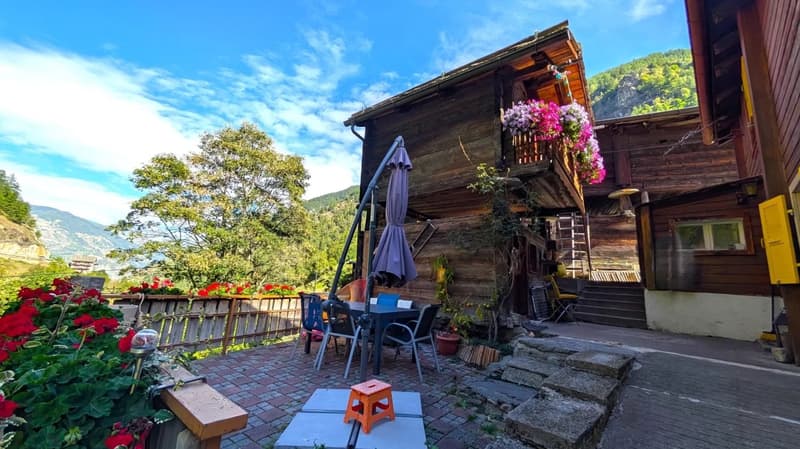 wooden chalet, balcony, patio table, flowers, view of the mountains