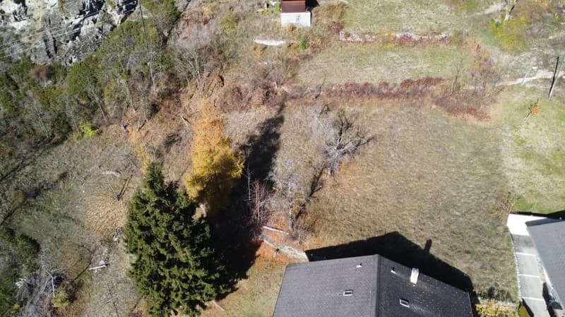 Empty lot with a shed and a house at the bottom right corner.