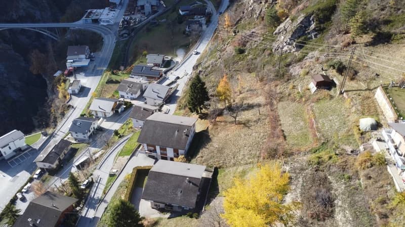 multiple buildings, small town, mountain setting, winding road, cars parked
