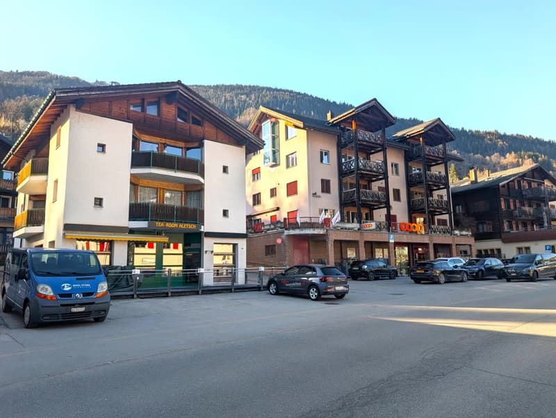 multiple story building, balconies, windows, parked cars, mountain in background