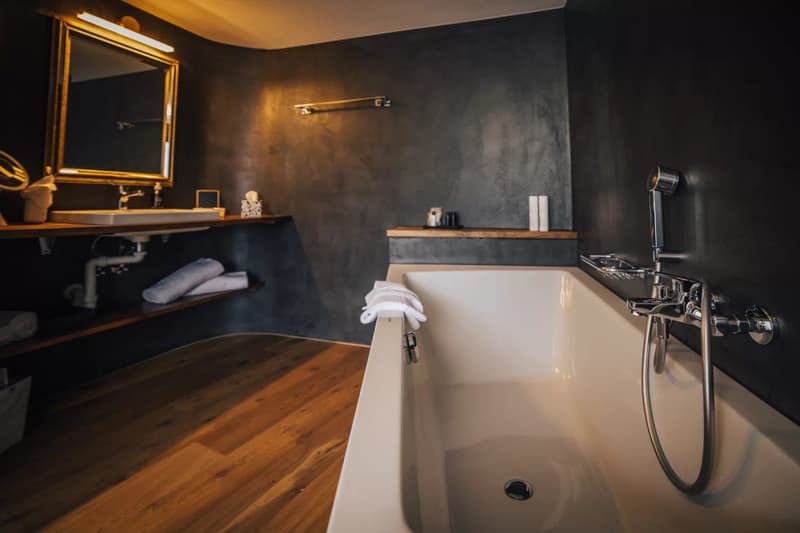 Bathroom with a bathtub, sink, mirror, and wooden floor
