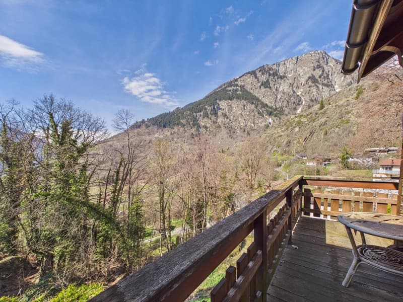 wooden balcony with railing, table and chair, mountain view