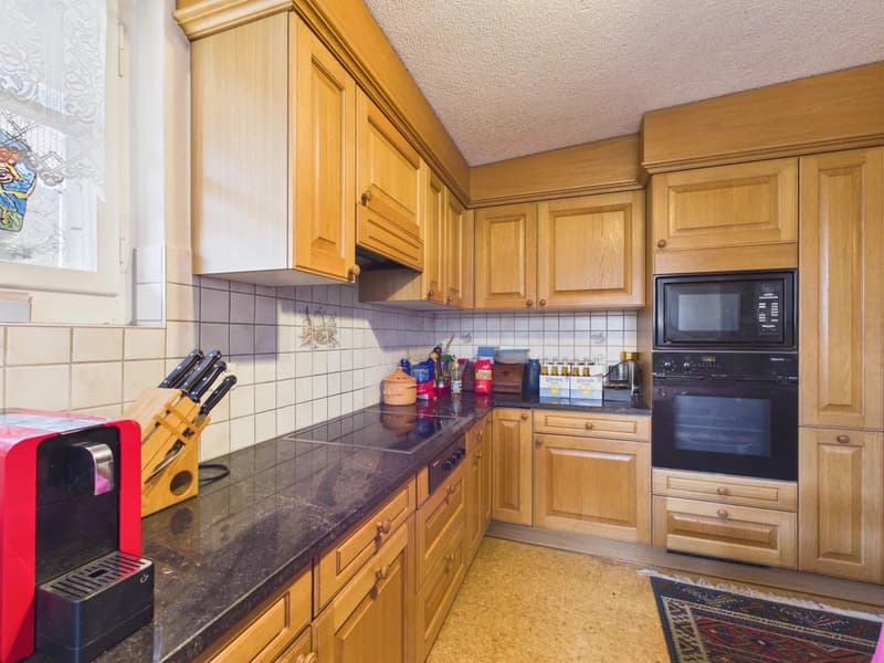 kitchen with wooden cabinets, granite countertop, black appliances, red coffee machine, tiled backsplash