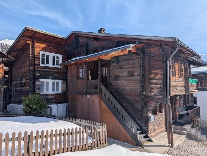Traditional wooden chalet, steep roof, wooden exterior, multiple windows, wooden stairs, wooden fence
